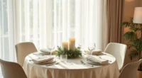 Round table with cream linen cloth, low evergreen and candle centerpiece, four place settings with folded napkins.