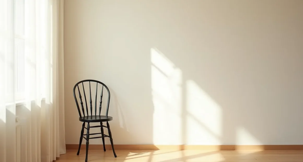 Iron chair with spindle back casting a sharp shadow on a neutral wall.