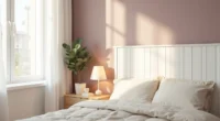 Mauve accent wall with white wooden headboard, cream bedding, potted eucalyptus on nightstand, and warm table lamp creating