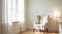Wingback armchair with rolled arms and high back sits alone in a bright corner against pale walls and light wood floor.