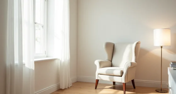 Wingback armchair with rolled arms and high back sits alone in a bright corner against pale walls and light wood floor.