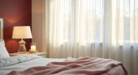 A burgundy accent wall corner with cream trim, white nightstand, blush throw, and lit white candle.